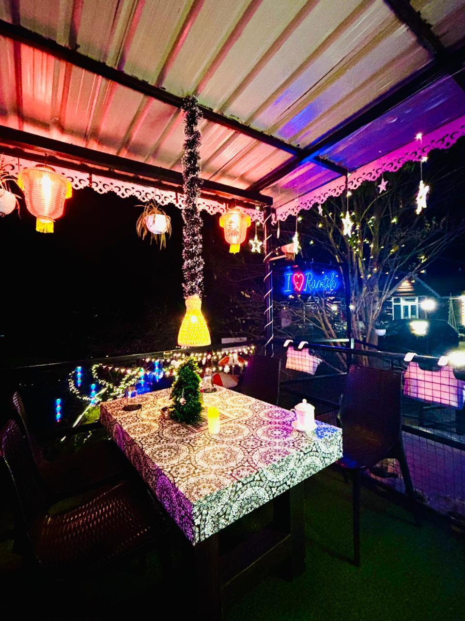 Covered restaurant seating with lanterns and neon signage at night