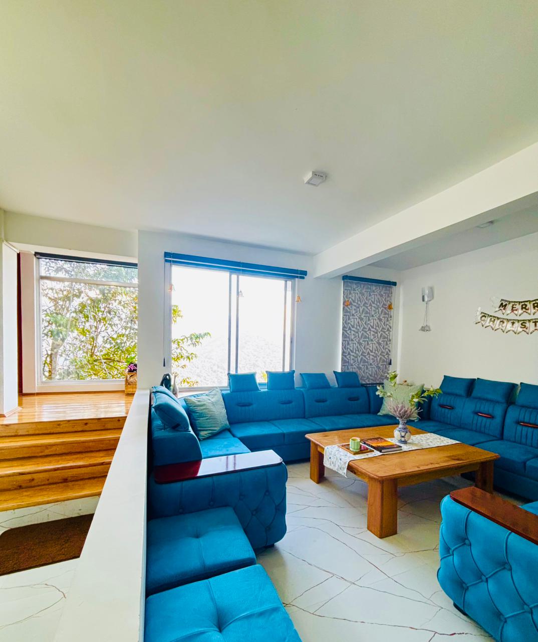 Shared lounge with blue sofas and large windows at Arosia By Mustard Seed
