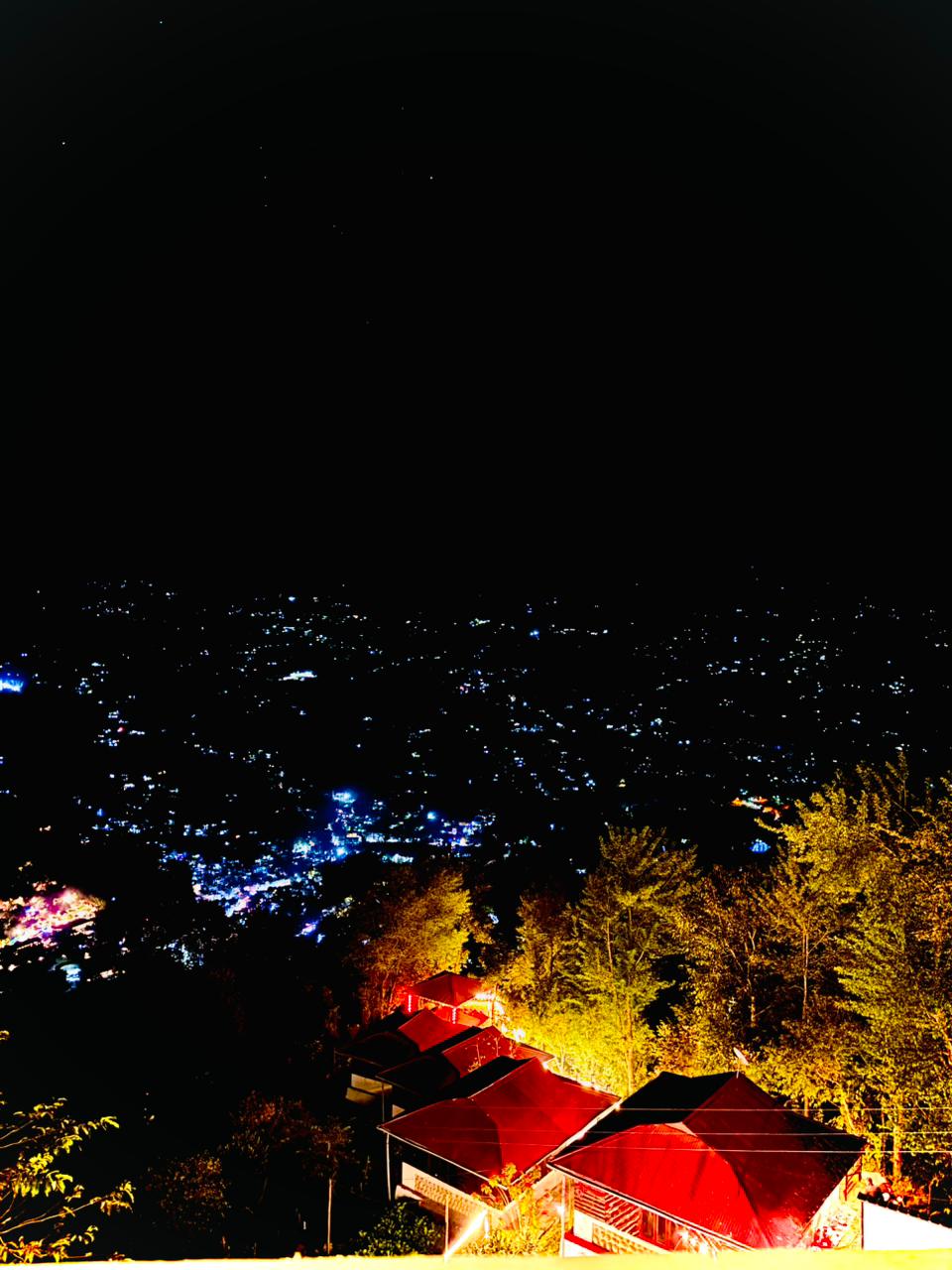 Night view of the lit cottages above the valley town lights