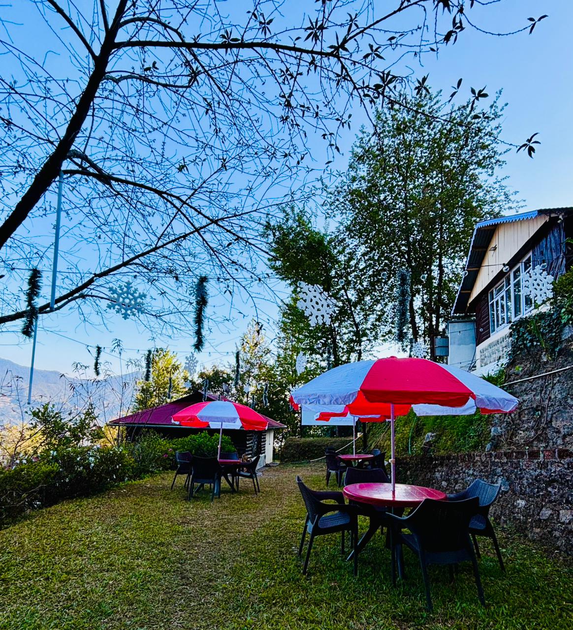 Outdoor garden seating with red parasols and mountain views