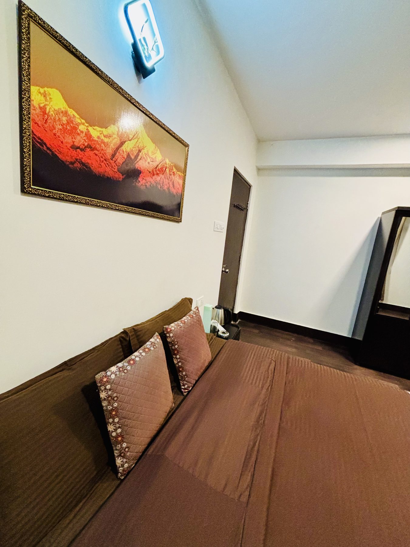 Bedside corner at Arosia by The Hive with framed Himalayan artwork and neon light
